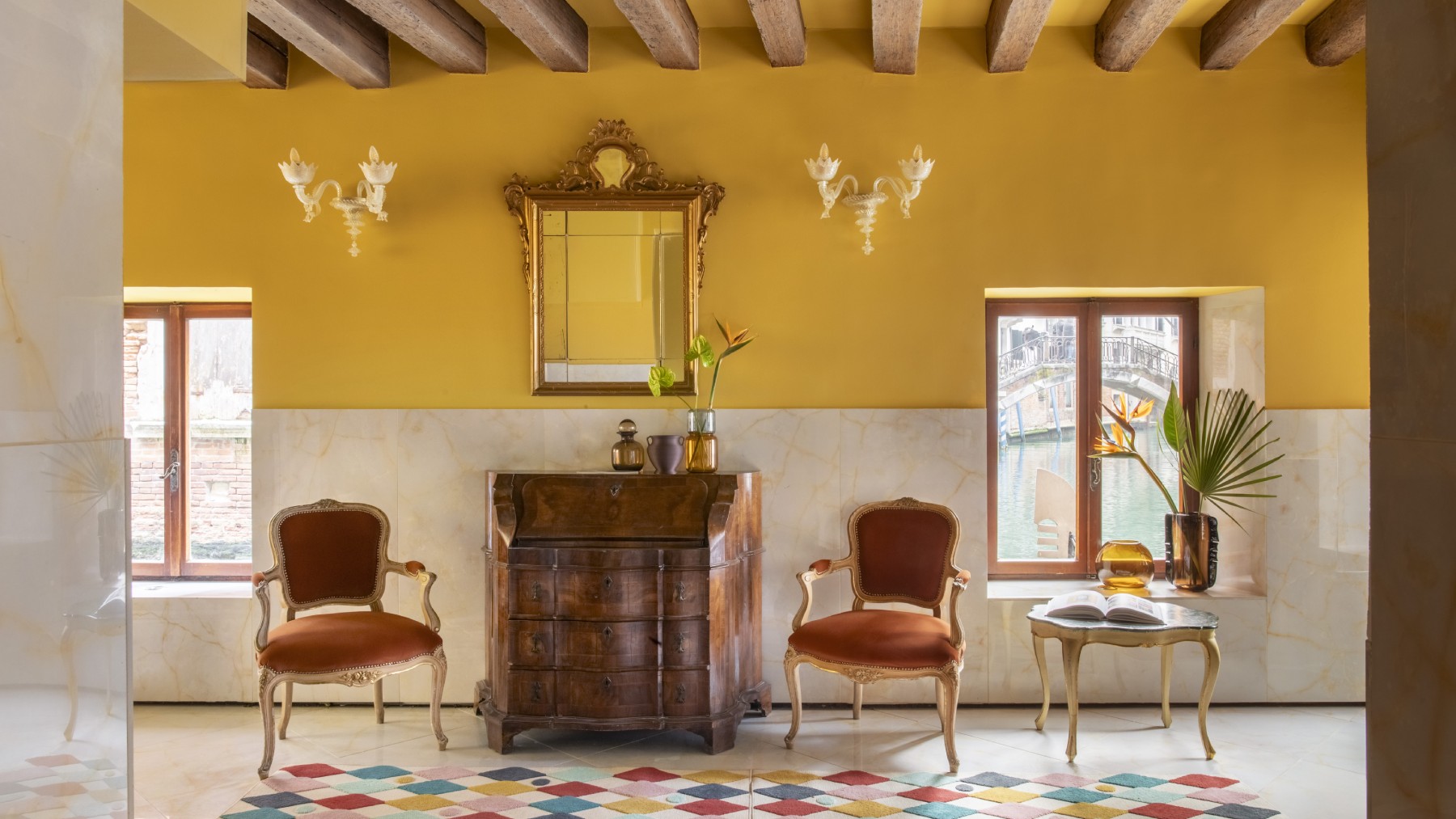 Area lounge di design Hotel Riva con pareti giallo senape, mobili vintage, travi a vista e finestre sul canale - Hotel Riva, BZAR hotels a Venezia