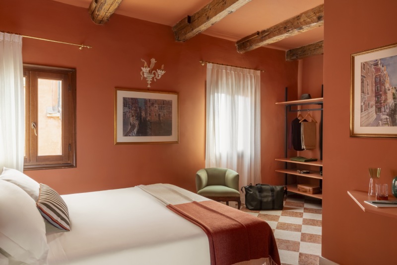 Burnt orange bedroom with exposed wooden beams, open-concept wardrobe, and checkered floor - Hotel Riva, BZAR hotels in Venice