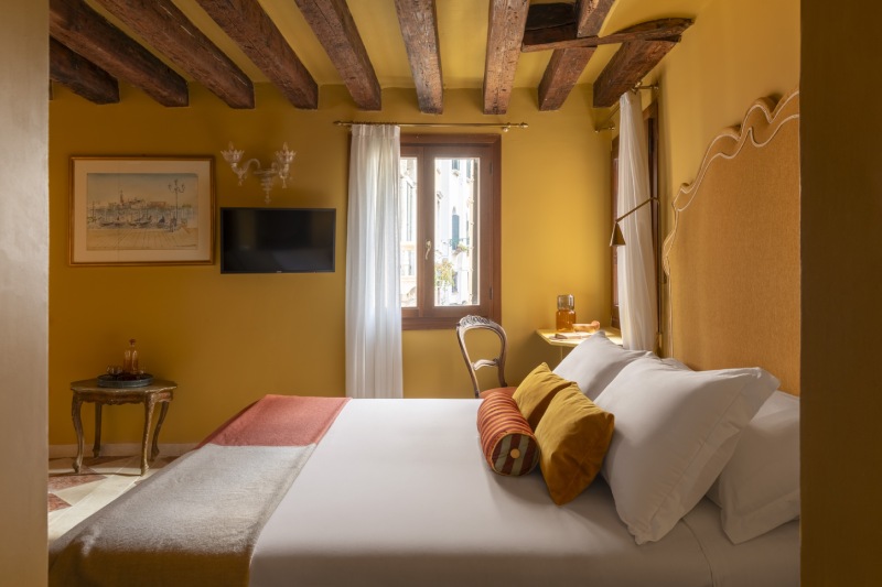 Triple room interior showing historic wood-beamed ceiling, ochre walls, and classic Venetian decor - Hotel Riva, BZAR hotels in Venice